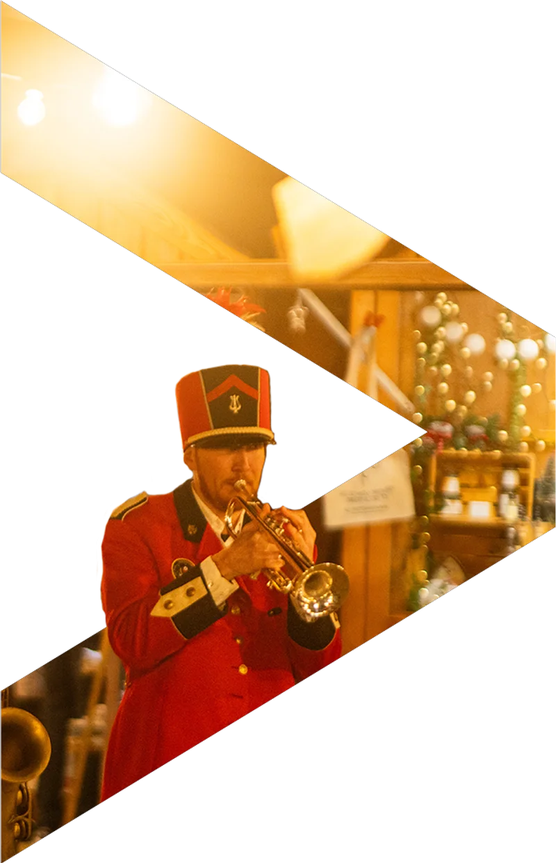 Musicien en uniforme rouge jouant de la trompette dans un marché de Noël